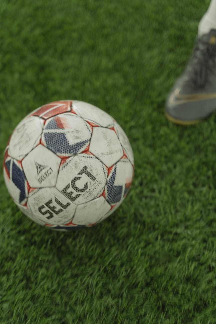 white and red soccer ball on green grass